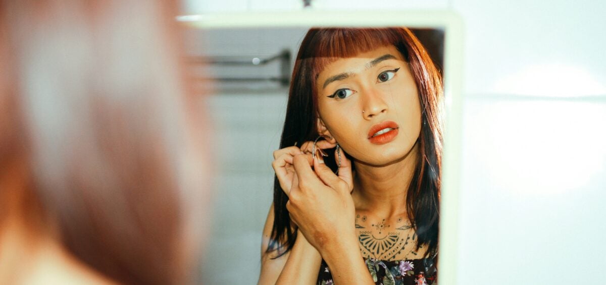 A person with gender dysphoria putting on earrings