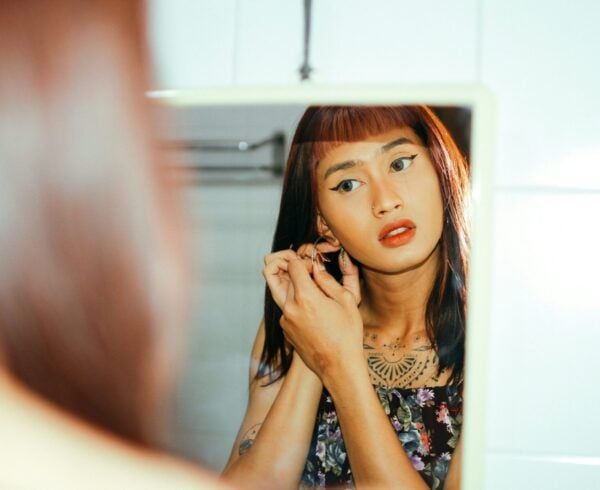 A person with gender dysphoria putting on earrings